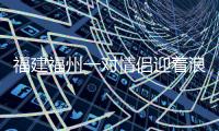 福建福州一對情侶迎著浪潮海中擁吻 期間女孩險被浪花沖倒